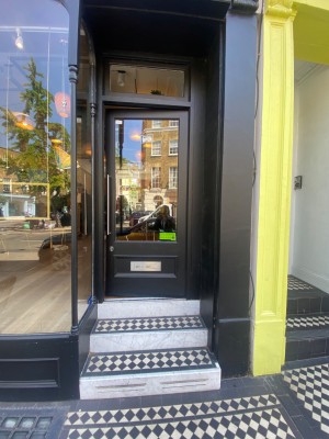 View of main entrance. One step from pavement to outside area. Move forward. Three steps then door. Bar handle on the left. Push to open. ...