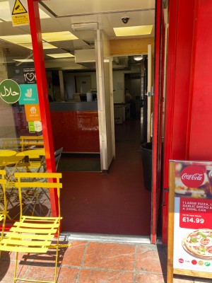 Glass door with red frame ahead Push handle on left to open.