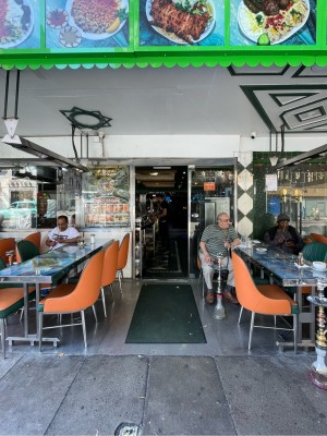 Facing entrance. Carpeted path in centre. Outdoor seating either side. Sliding metal-framed glass door at end of path.
