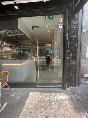 Facing entrance. Outdoor seating on left. Single glass door ahead. Push vertical silver handle on left to open.