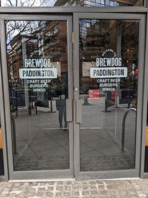 Glass doors with grey frame and grey handles in centre. Pull to open.