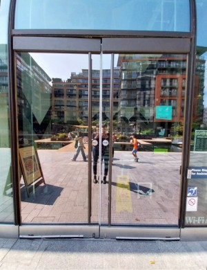 Glass doors in brown frame. Push from centre to open. Push button on right to open.