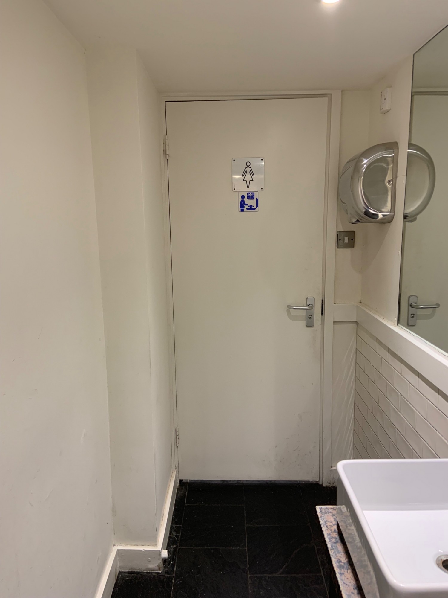 From sink counter looking left. Ladies bathrooms straight ahead. Door pull to open via small handle on right side.