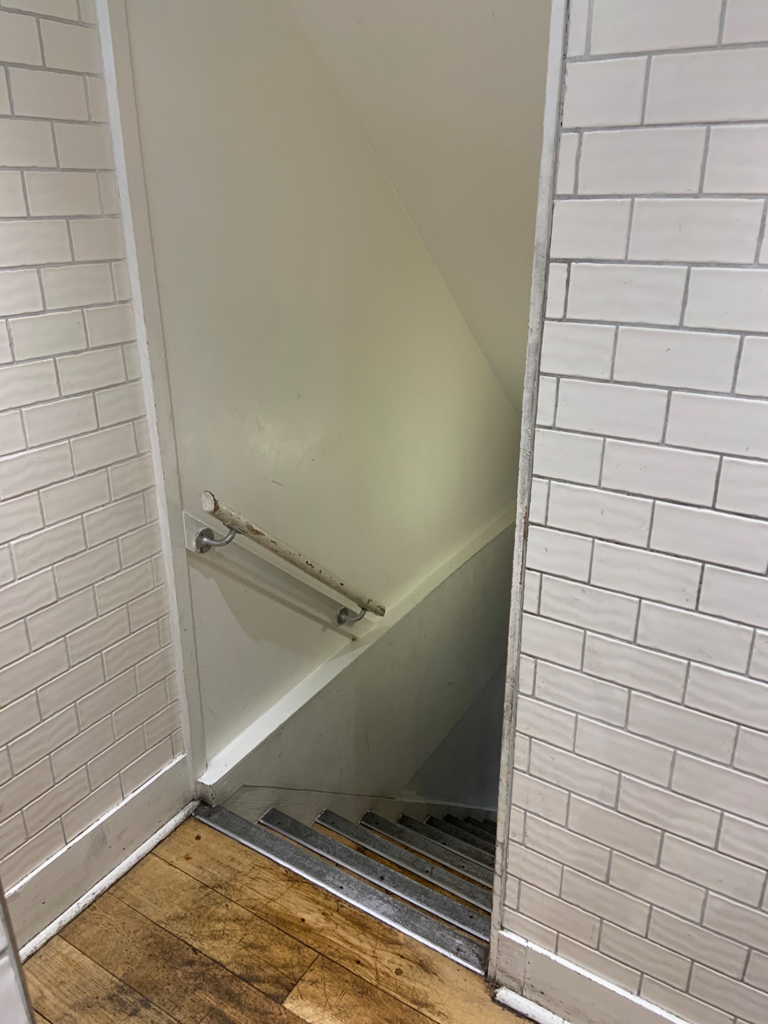 View of archway at top of staircase. Handrail along start of left side of wall.