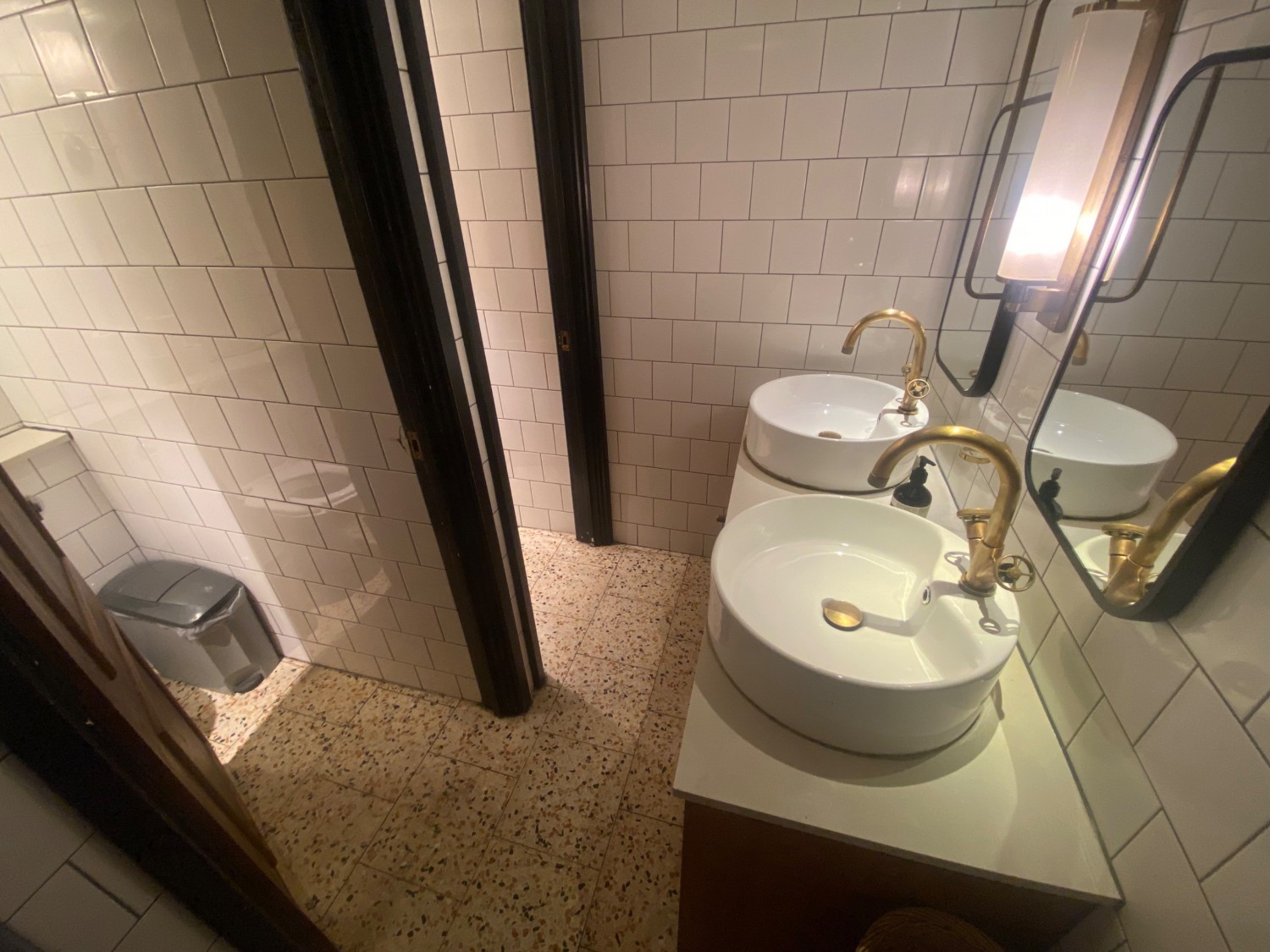 From door facing straight. Sink along right. Path in centre. Toilet cubicles along left.