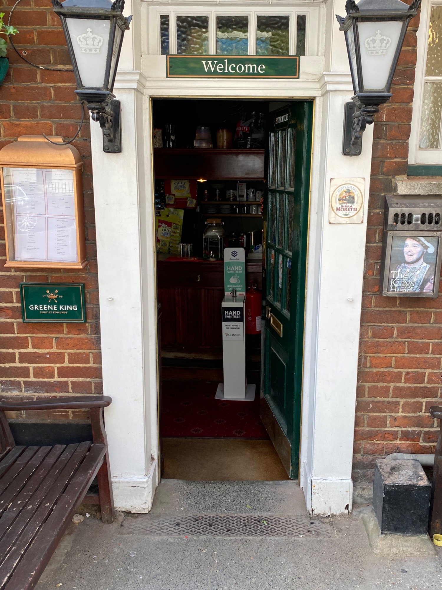 White framed green glass door. One concrete step along centre. Push on left side of door to open.
