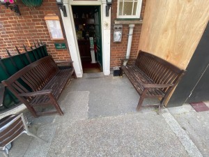 Facing entrance. Path ahead. Wooden benches on left and right. Door at end of path.