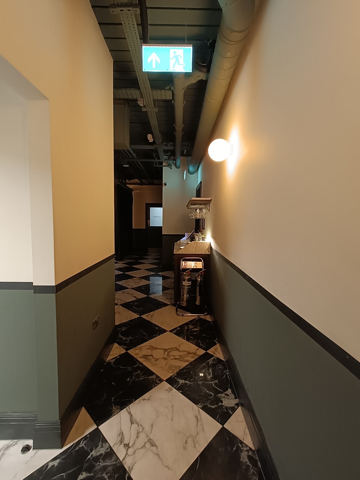From bottom of stairs, looking straight. Pillar on left. Host desk at back right. Path in middle.