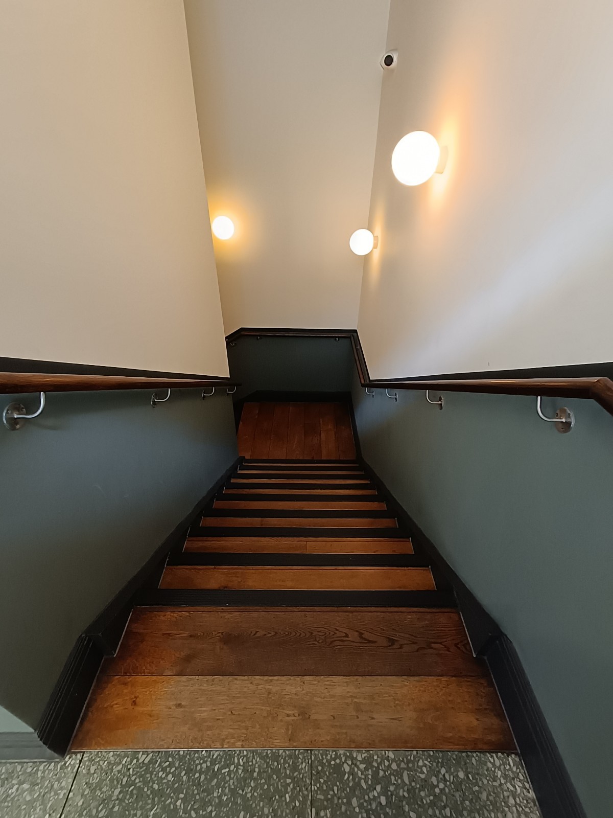 From bathroom, looking right. Stairs ahead. Brown handrails on both sides.