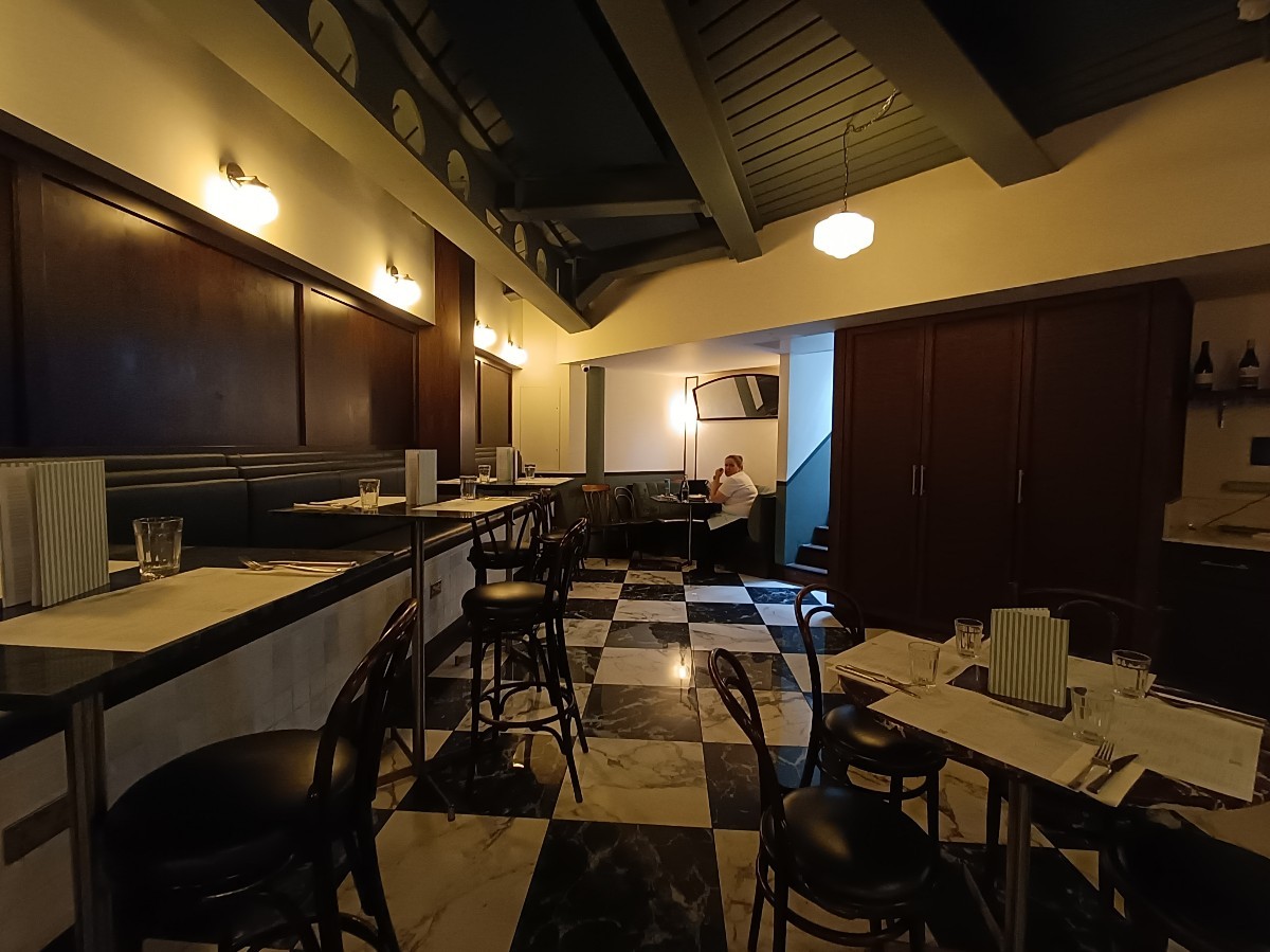 From end of path, looking right. Tables and stools along left. Tables and chairs on right. Path in middle.