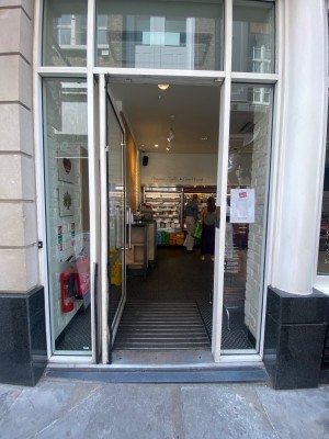 Glass door ahead. Push to right via vertical metal handle to open.