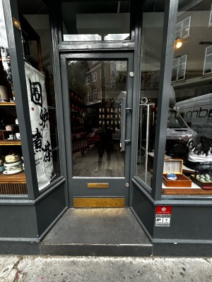 Glass single door with wooden grey frames. Silver handle on mid right. Push to open