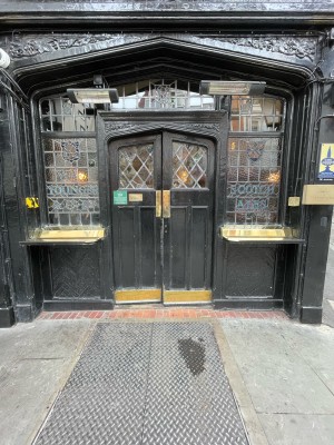 Facing entrance. Black wooden doors ahead. Windowsills either side. No handles. Push doors at centre to open.