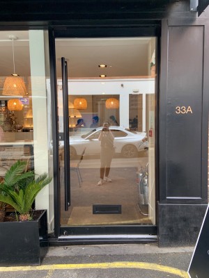 Single glass door with long black vertical handle along left. Push to open.