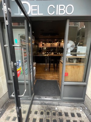 Glass door with black frames ahead. Pull to right via vertical metal handle.