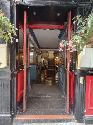 Facing red framed double doors. Pull golden metal handles in centre to open. Doorbell for assistance on right of door.