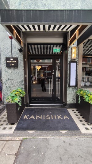 From sidewalk facing venue. Path ahead with a doormat before door.