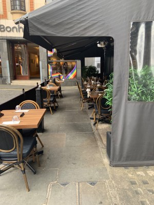 View of entrance to outdoor area before entrance doors on right side of venue. Seating along dividing wall to left with pathway in centre. Turn right for entrance door.