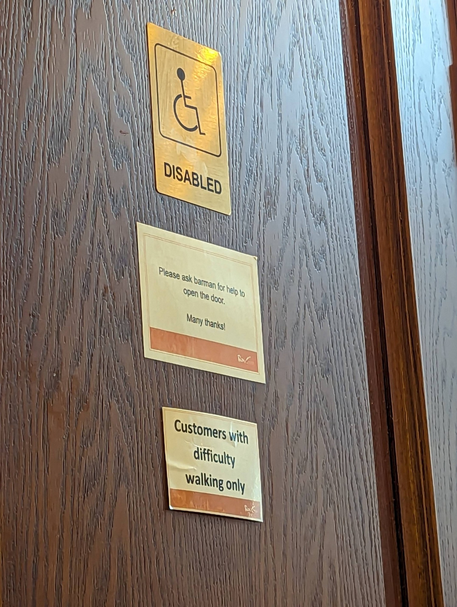 Signs says "please ask barman for help to open the door" and "customers with mobility issues only"