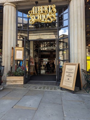 Glad double door entrance propped open. Two sets of glass doors with sloping ramp leading to inside