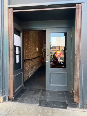 Double black framed glass push doors with handles in middle at standing height. Built in ramp after doors.