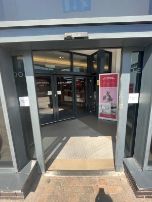 Double automatic doors with small bump before it. After entering there is a path and next set of doors on the left.