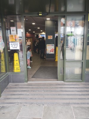 Picture of main entrance. It is an automatic door that slides open to the right. There is a built-in ramp.