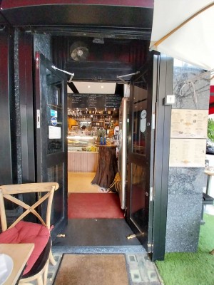 Glass door with silver handrail on mid left. Push to open