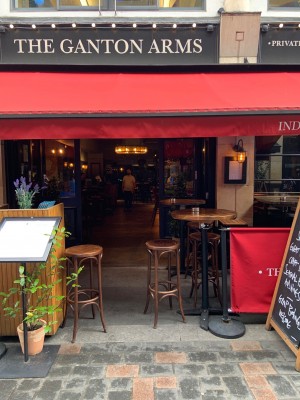 View of front of venue from street. Gap in dividing barrier to outside area with pathway straight to main entrance. Stools slightly obstructing entrance.