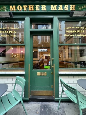 Glass door with green frames ahead. Push to right to open via vertical gold handle.