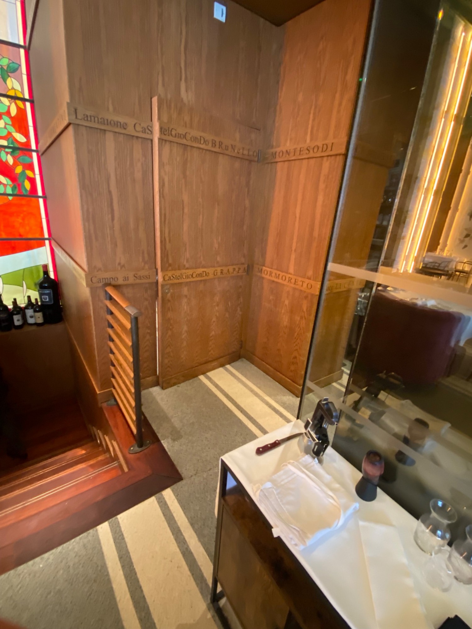 Pathway to bathroom located on right side at top of staircase. Pathway partially obstructed by staircase barricade on left and table on right.