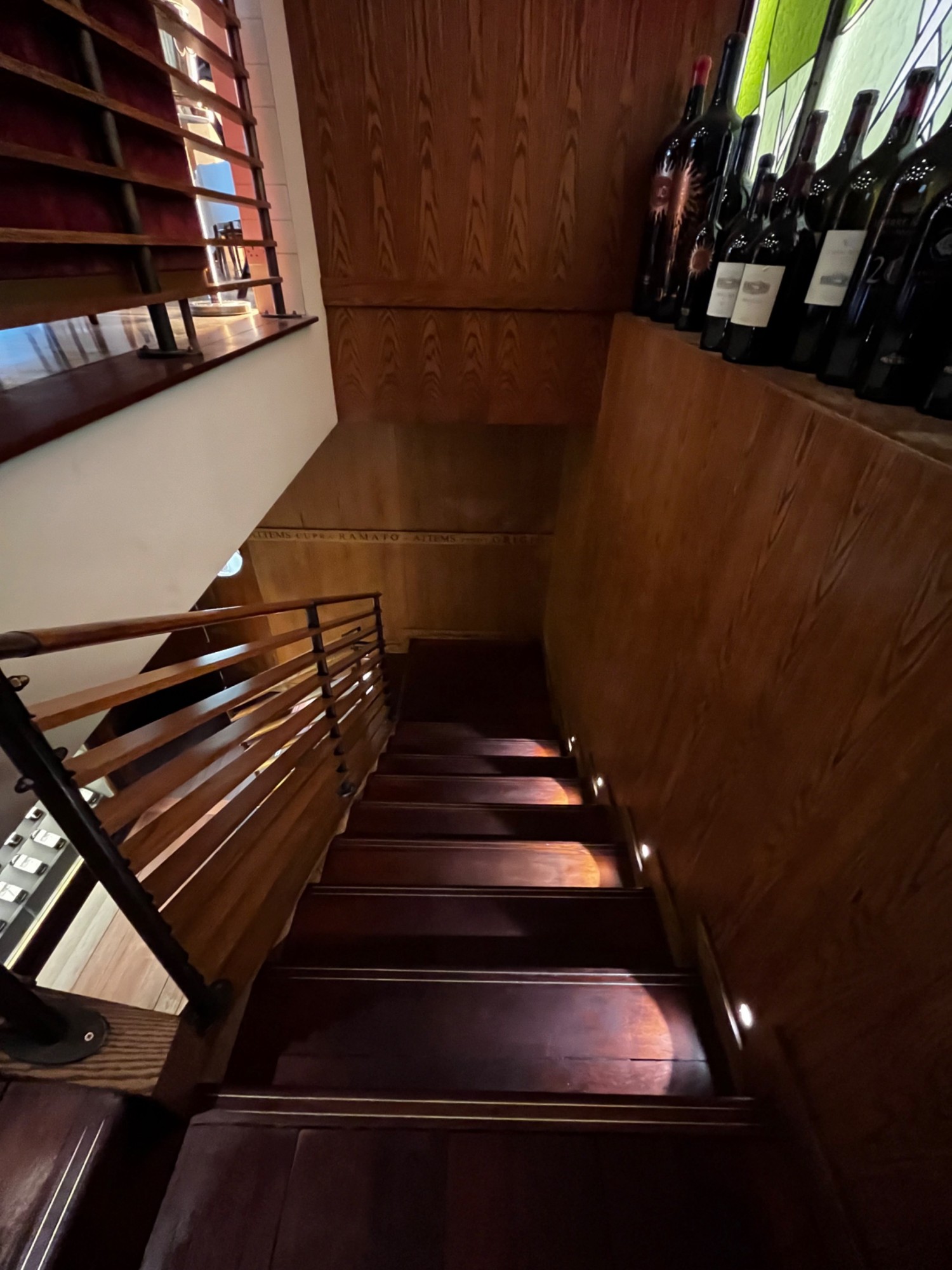 Continuation of downstairs staircase facing left from first landing. Handrail on left. Staircase continues left again at second landing.
