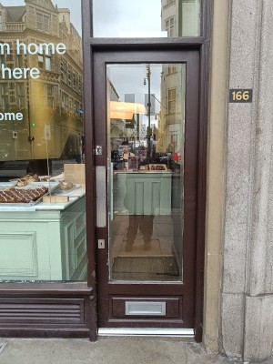 Glass door with brown wooden frame. Push silver metal pad on left to open. Carpet with slight slope up after door.