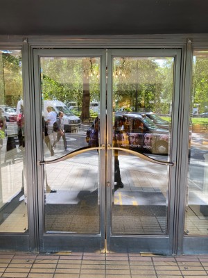 Main entrance to Park Room along Park Lane. First set of doors black framed glass pull manual doors with handles horizontal along door.