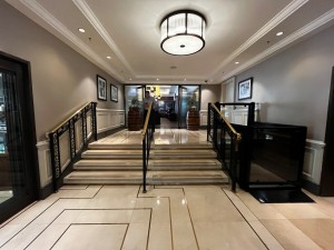 Main entrance to restaurant. Stairs divided in middle by handrail with handrails either side. Platform lift on right of stairs.