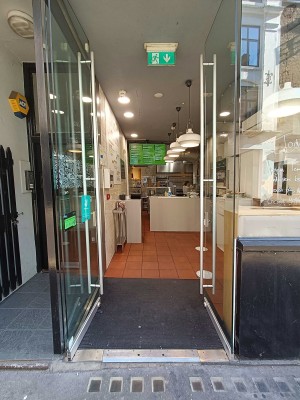 Glass doors ahead. Push in centre by vertical metal handles to open.
