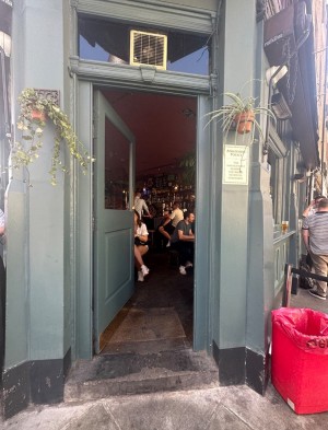Glass door with blue frame. Golden, metal pad on right. Push to open.
