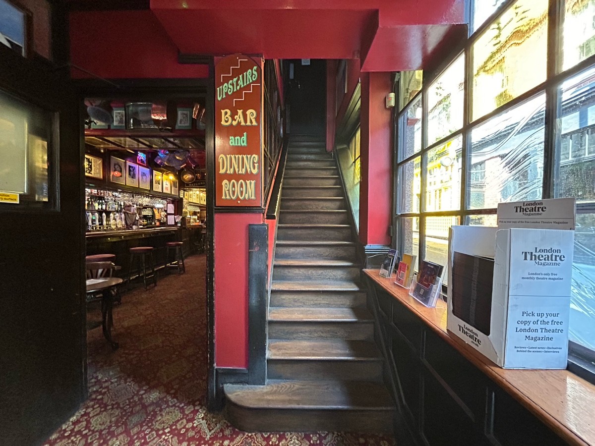 From first door facing straight. Staircase ahead up to private room. Second doorway on back left to main area.