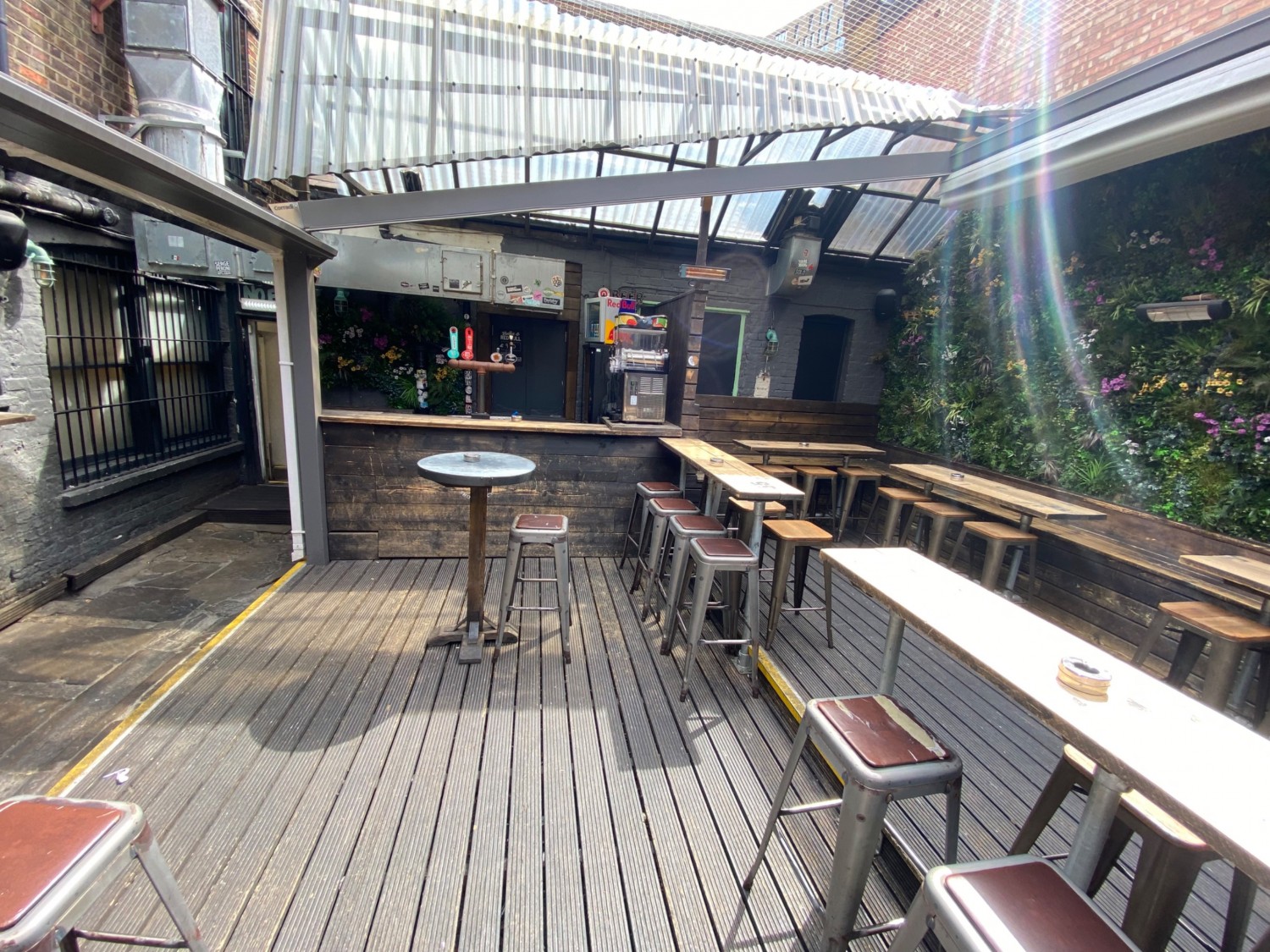 View to left side of first seating platform. Bar along back wall with high table in front. Seating along right side with gap in centre to upper seating.