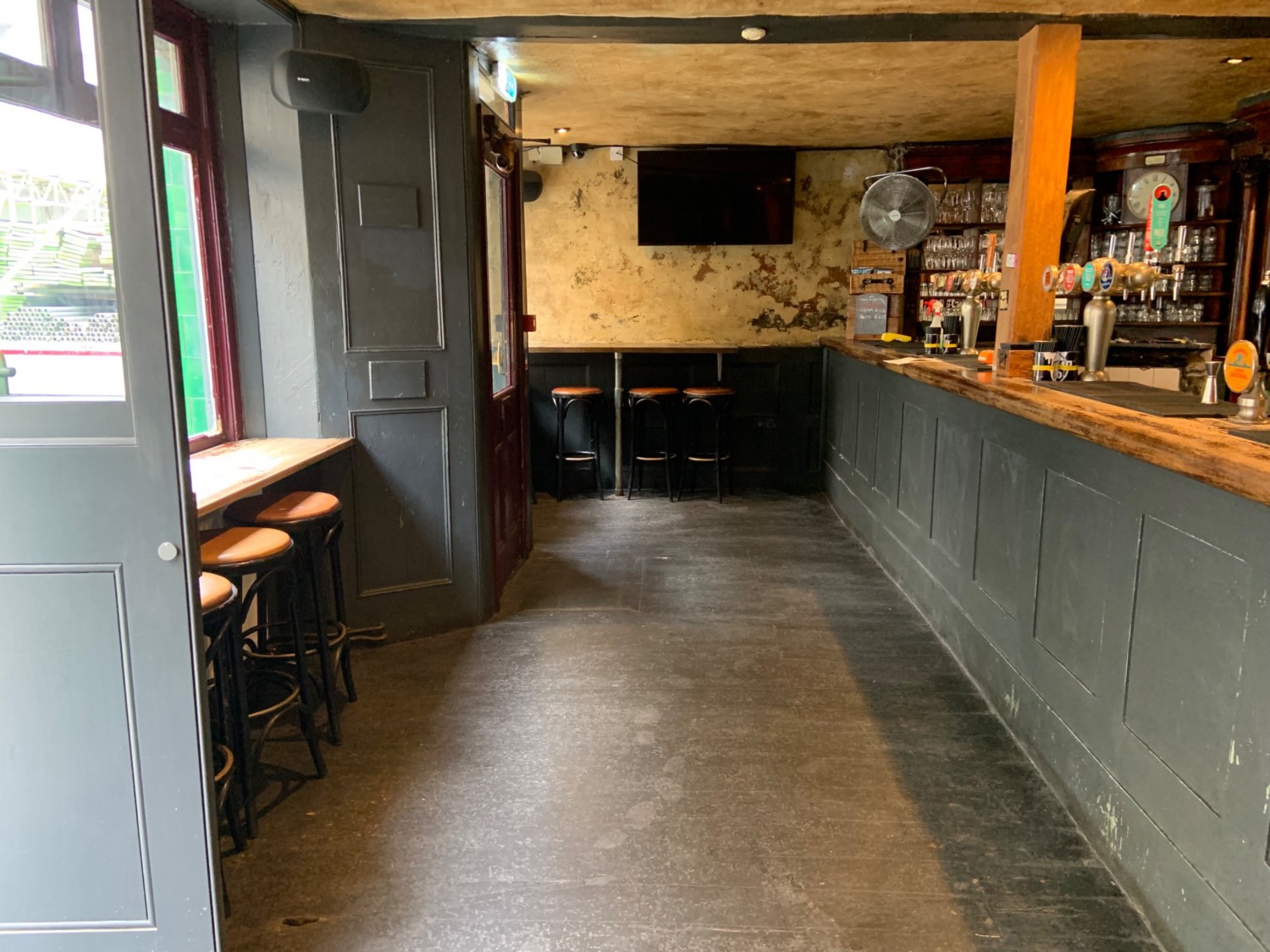 From entrance looking left. Bar along right side. Wide pathway centre. Seating along back and left walls.