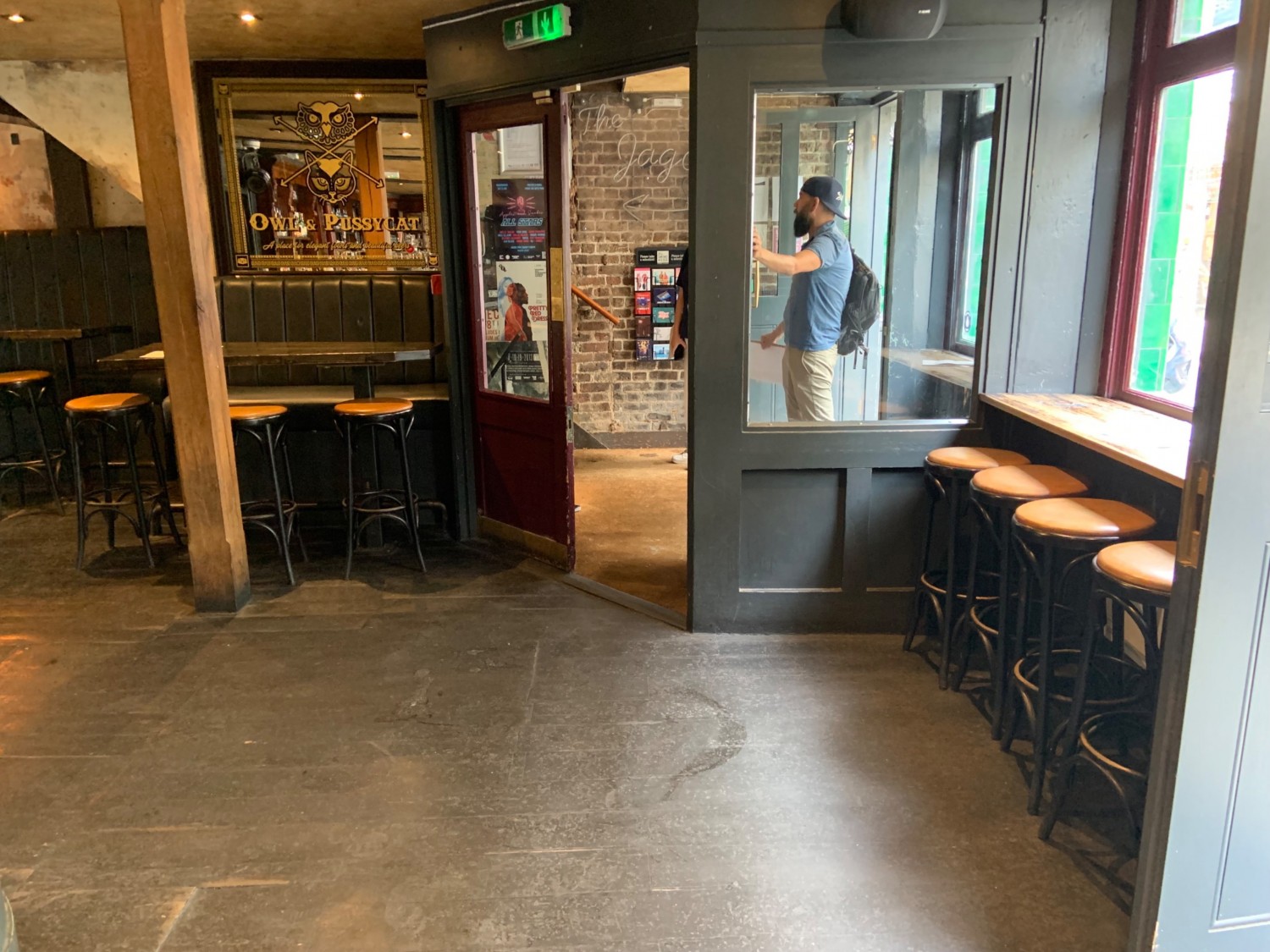 From entrance looking right. Seating along right wall. Accessible entrance in centre right of back wall. Seating to left of doors with pillar in front. Wide pathway in front leading to further seating to left.