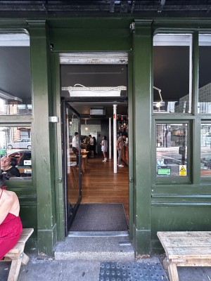 Facing single glass door with black frames. Push black handle on right to open.