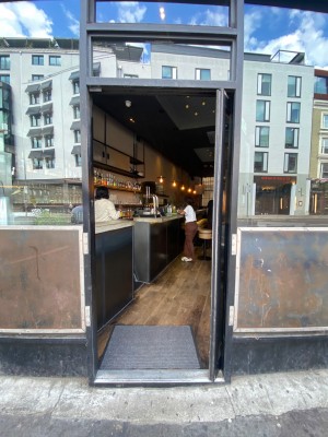 Main glass and black door straight ahead. Push to open. Handle left side.