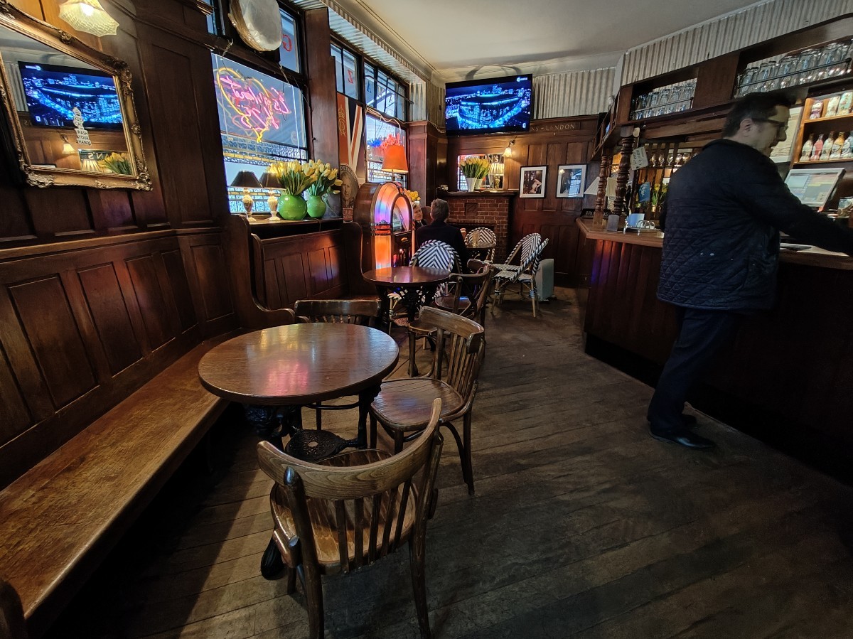 From entrance facing left. Half booth along left. Gaming machine and tables and chairs behind.