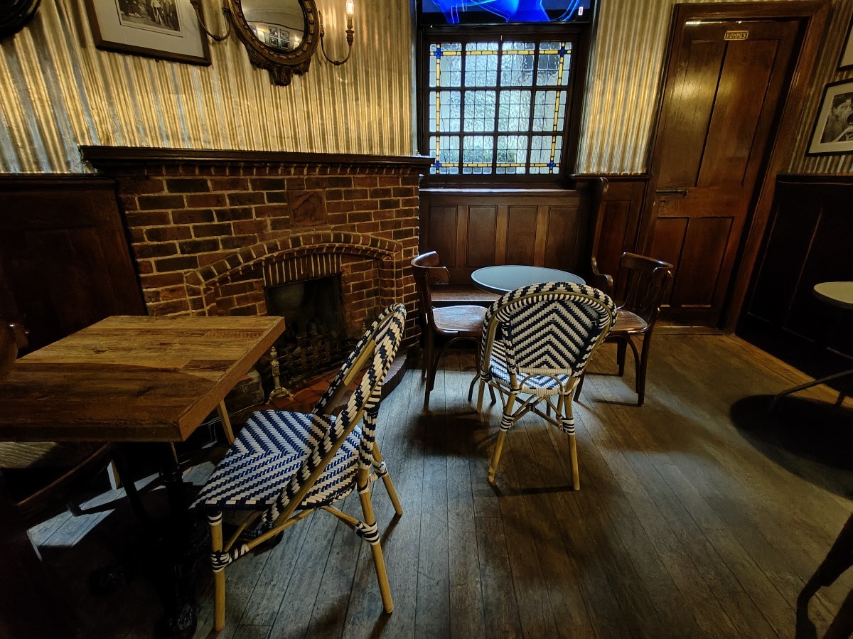 From end of bar facing straight. Tables and chairs ahead. Male bathroom on right.