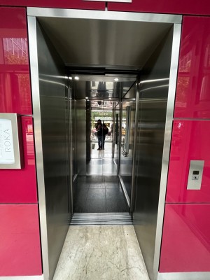 From path, facing lift. Call button on right. Doorway at back.