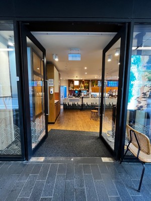 Glass door with black, metal frame. Push silver handle in middle to open.