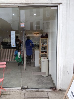 Glass door with metal handle on left. Push to open.