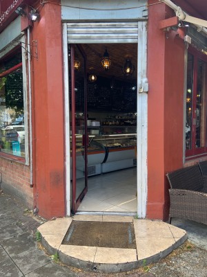 Main entrance glass door with red frame and colour contrasted white doorway. Push to open on right side.