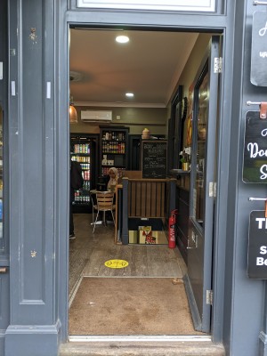Glass door with grey frame and metal handle on left. Push to open.